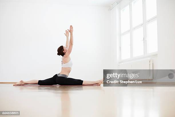 side view of woman in exercise arms raised doing the splits - doing the splits stock pictures, royalty-free photos & images