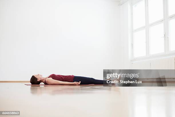 woman in exercise studio lying on back on floor - supino foto e immagini stock