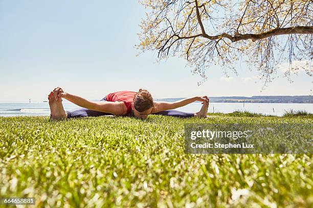 woman bending forward in yoga position, touching toes - older woman bending over stock pictures, royalty-free photos & images