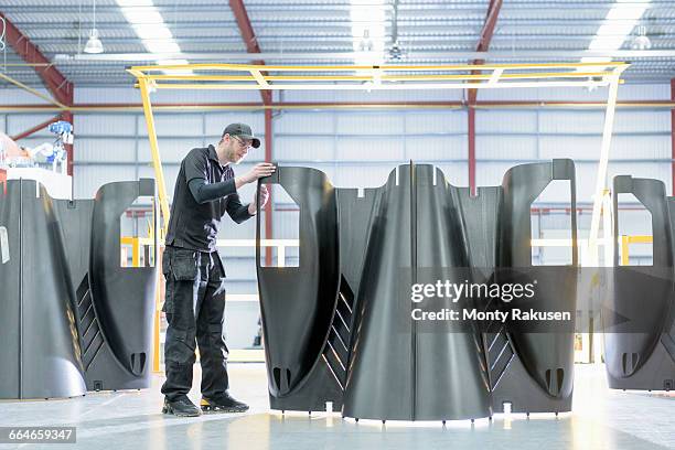 engineer inspecting carbon fibre body parts in racing car factory - carbon fibre stockfoto's en -beelden