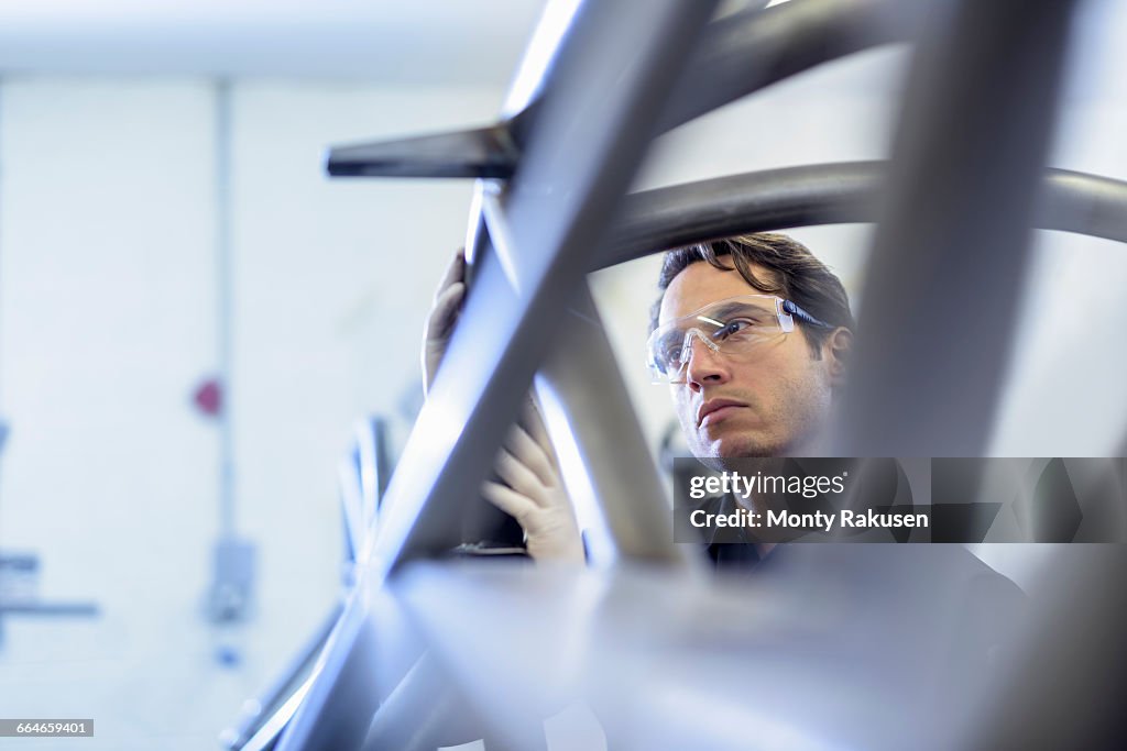 Engineer inspecting racing car roll cage in racing car factory