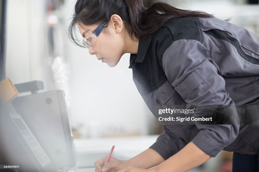 Technician writing notes in factory