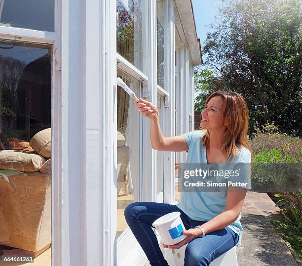 woman painting window frame - windowframe stockfoto's en -beelden