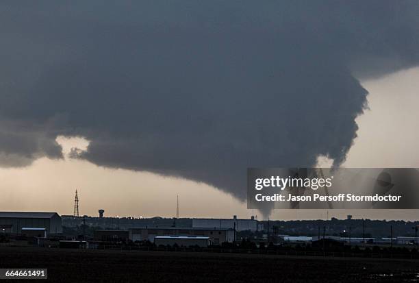 a cone tornado touches down from a very large wall cloud as it threatens dodge city, kansas, usa - dodge-city-kansas stockfoto's en -beelden
