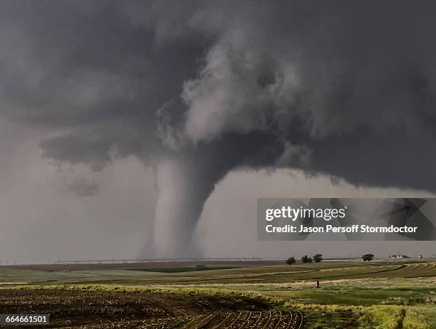 a large cone tornado touches down over the open prairie - tornado stockfoto's en -beelden