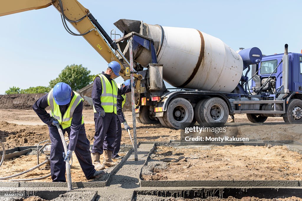 Apprentice builders laying concrete foundations on building site