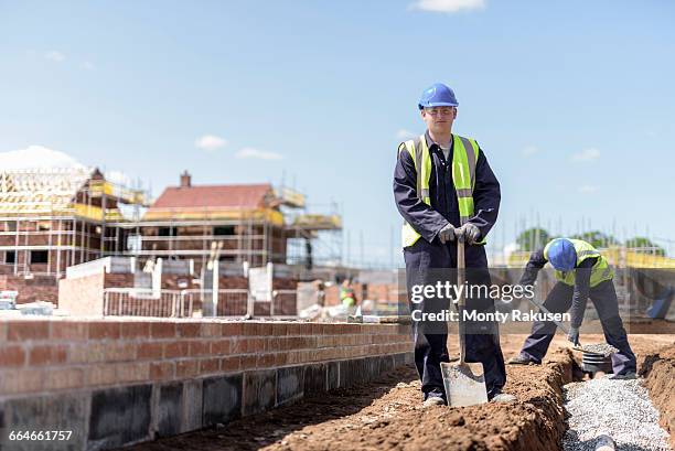 portrait of apprentice builder laying pipework on housing building site - trench safety stock pictures, royalty-free photos & images