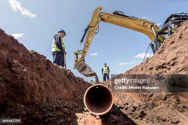 builders laying pipework on housing building site - excavator fotografías e imágenes de stock