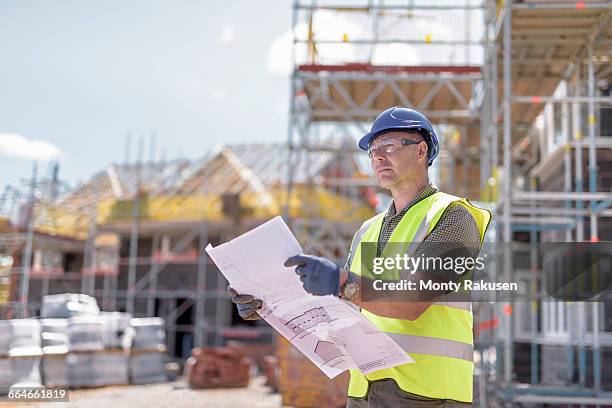 site manager looking at plans on housing building site - protective workwear construction stock pictures, royalty-free photos & images