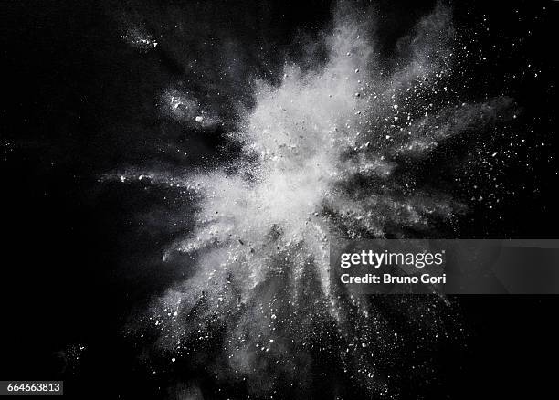 white dust exploding mid air against black background - spring stockfoto's en -beelden