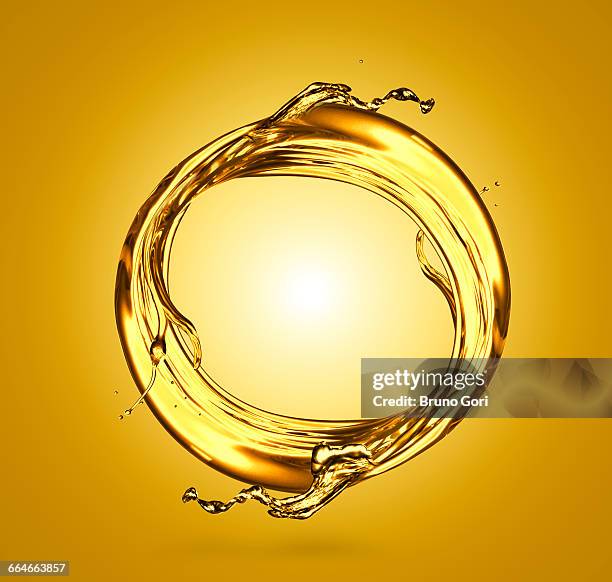 transparent liquid swirling against yellow background - liquid foto e immagini stock