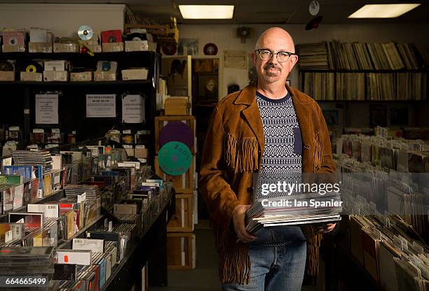 portrait of mature man in record shop, holding records - plattenladen stock-fotos und bilder