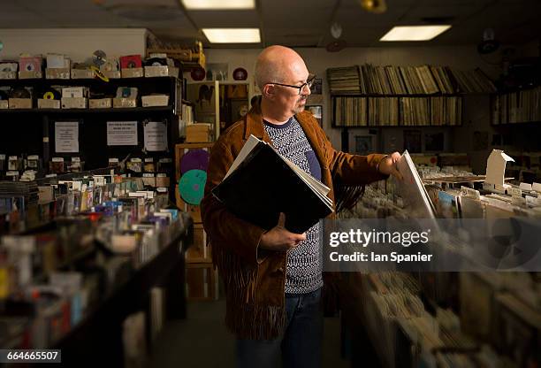 mature man in record shop, filing records - plattenladen stock-fotos und bilder