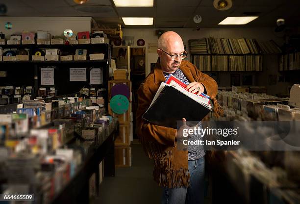 mature man in record shop, sorting through records - plattenladen stock-fotos und bilder