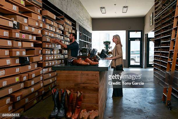cobbler selecting shoebox for female customer in traditional shoe shop - shoe repair stock-fotos und bilder