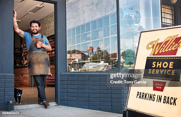 portrait of male cobbler leaning against shoe shop doorway - 靴修理人 ストックフォトと画像