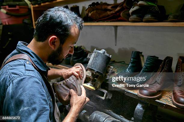 male cobbler in traditional shoe workshop inspecting boot - sapateiro imagens e fotografias de stock