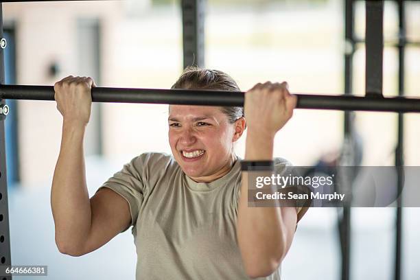 determined female soldier doing pull ups at military air force base - campamento de instrucción militar fotografías e imágenes de stock