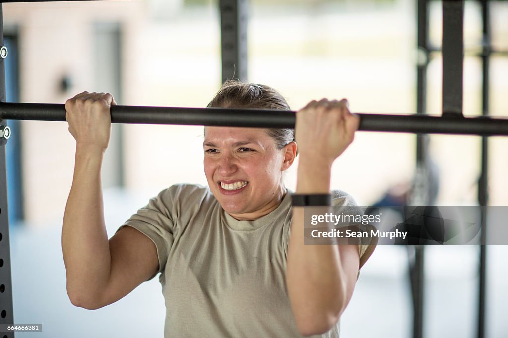 Determined female soldier doing pull ups at military air force base