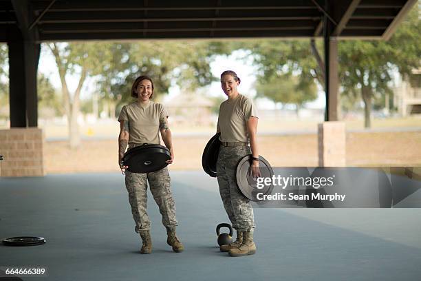 portrait of two female soldiers barbell training at military air force base - military base foto e immagini stock