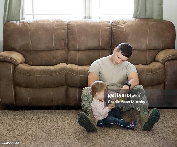 male soldier playing with daughter in living room at air force military base - home base stockfoto's en -beelden