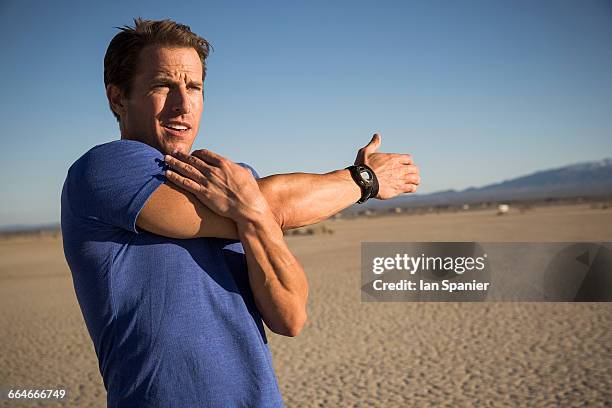 man training, stretching arms and shoulder on dry lake bed, el mirage, california, usa - dried lake bed stock pictures, royalty-free photos & images