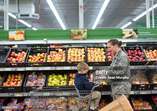 female soldier shopping with son in supermarket at air force military base - military base foto e immagini stock