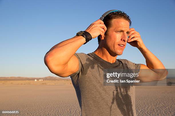 man training, putting on headphones on dry lake bed, el mirage, california, usa - el mirage photos et images de collection