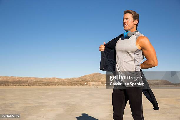 man training, putting on tracksuit top on dry lake bed, el mirage, california, usa - el mirage photos et images de collection