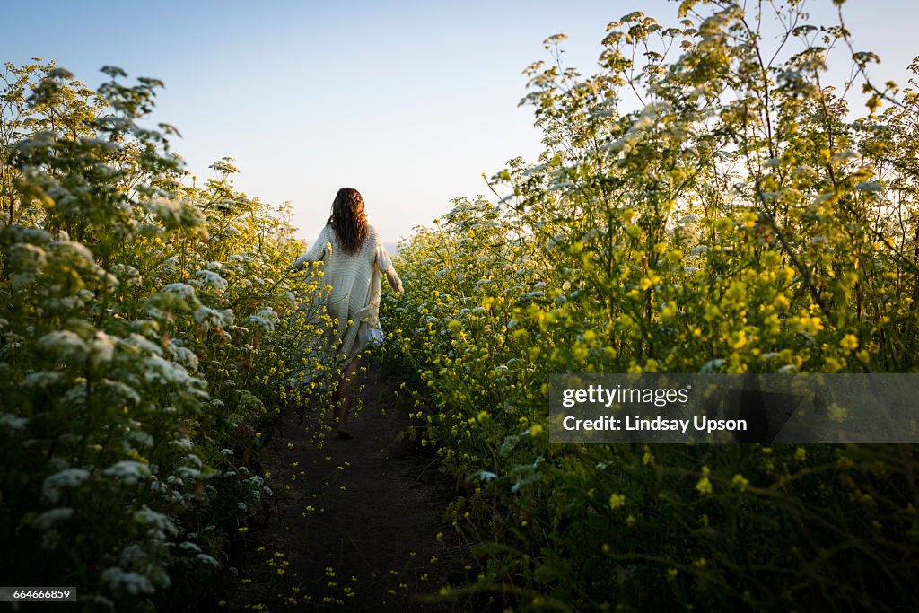 Woman walking through field of wildflowers