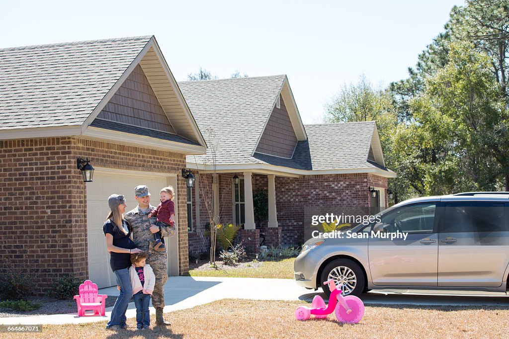 Portrait of male soldier, pregnant wife and daughters in garden at air force military base