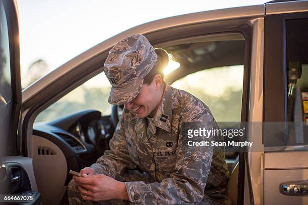 female soldier sitting in car texting on smartphone at air force military base - air vehicle 個照片及圖片檔
