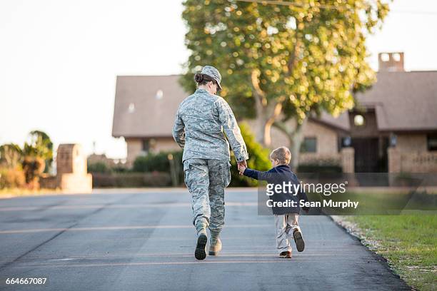 rear view of female soldier walking with son at military air force base - us air force stock-fotos und bilder