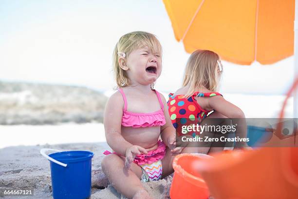 two sisters sitting on beach, toddler crying, cape town, south africa - crying sibling stock pictures, royalty-free photos & images