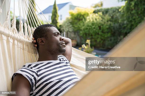 young man reclining on garden hammock - reclining hero stock pictures, royalty-free photos & images