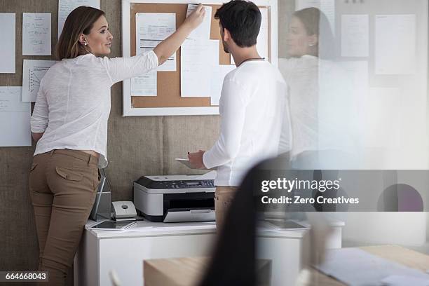 female designer pinning plans on notice board in design studio - pin up girl stockfoto's en -beelden