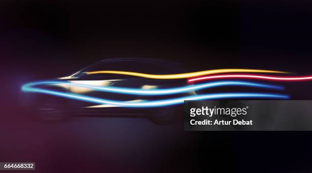 long exposure of a beautiful suv car with aerodynamic design in motion at night with colorful light trails in black background in a futuristic and creative picture. - futuristic cars foto e immagini stock
