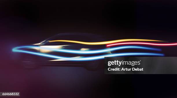 Long exposure of a beautiful SUV car with aerodynamic design in motion at night with colorful light trails in black background in a futuristic and creative picture.