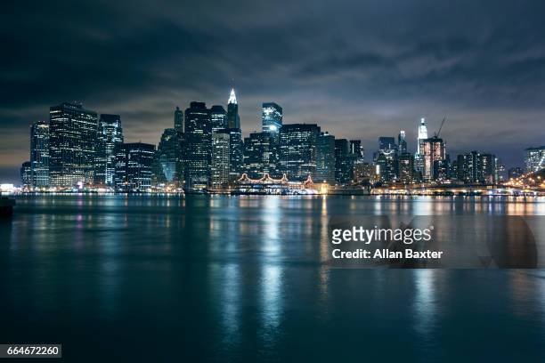 skyline of lower manhattan in new york illuminated at night - orizzonte urbano foto e immagini stock