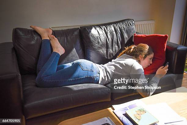 girl on couch with smart phone - jeans barefoot fotografías e imágenes de stock