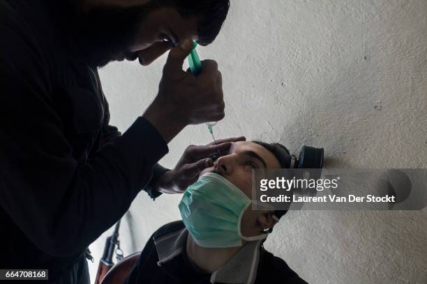 Rebel fighter with Liwa Tahrir al Sham receive prednisolone acetate in eye drops to treat their exposure to sarin gas earlier that week in Jobar, a...