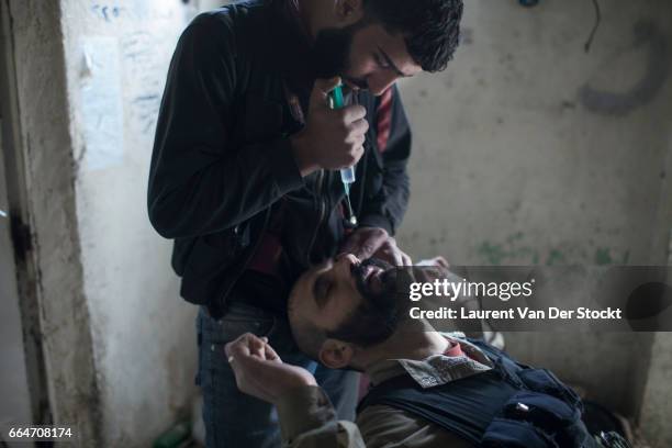 Rebel fighter with Liwa Tahrir al Sham receive prednisolone acetate in eye drops to treat their exposure to sarin gas earlier that week in Jobar, a...