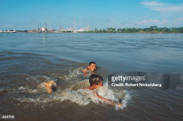 Children swim on the Yondo side of the Magdalena River August 21, 2000 near the site of Colombia's largest petroleum refinery. President Andres...