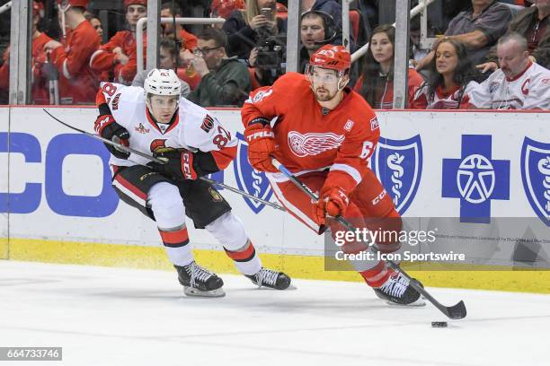 Detroit Red Wings defenseman Xavier Ouellet brings the puck up ice followed by Ottawa Senators center Colin White during the NHL hockey game between...