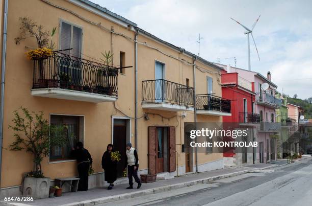 Some citizens of Montelongo walking in the streets of the village surrounded by wind turbines of Montelongo wind farm in Molise, southern Italy. One...