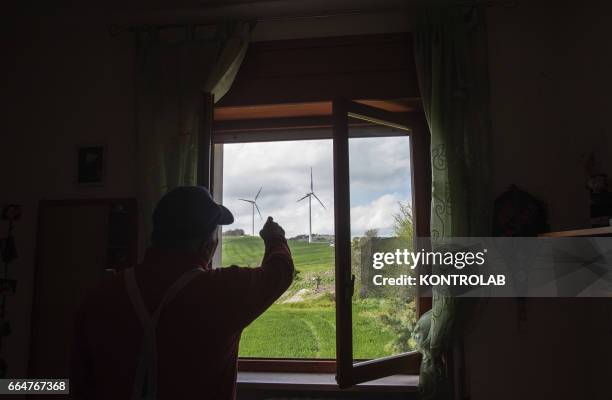 Citizen of Montelongo pointing with hand turbines of Montelongo wind farm in Molise, southern Italy. One of the biggest wind farms of southern Italy...