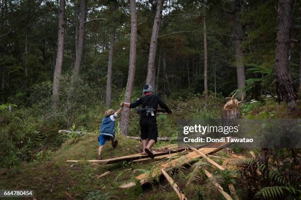 Ka Rodel guides the hand of his 6 year old brother in the dense upland vegetation of the camp on April 1, 2017. A former scavenger in the tough urban...