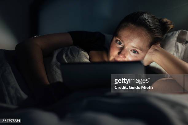 woman using home tablet pc in bed. - parte de una serie fotografías e imágenes de stock