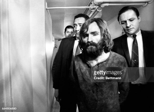 Charles Manson, accused leader of a hippie cult charged with the Tate-LaBianca murders, leaves court after deferring a plea on the murder charges....