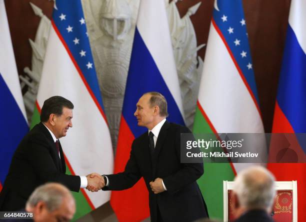 Russian President Vladimir Putin and Uzbek President Shavkat Mirziyoyev shake hands at the signing ceremony at the Grand Kremlin Palace on April 5,...